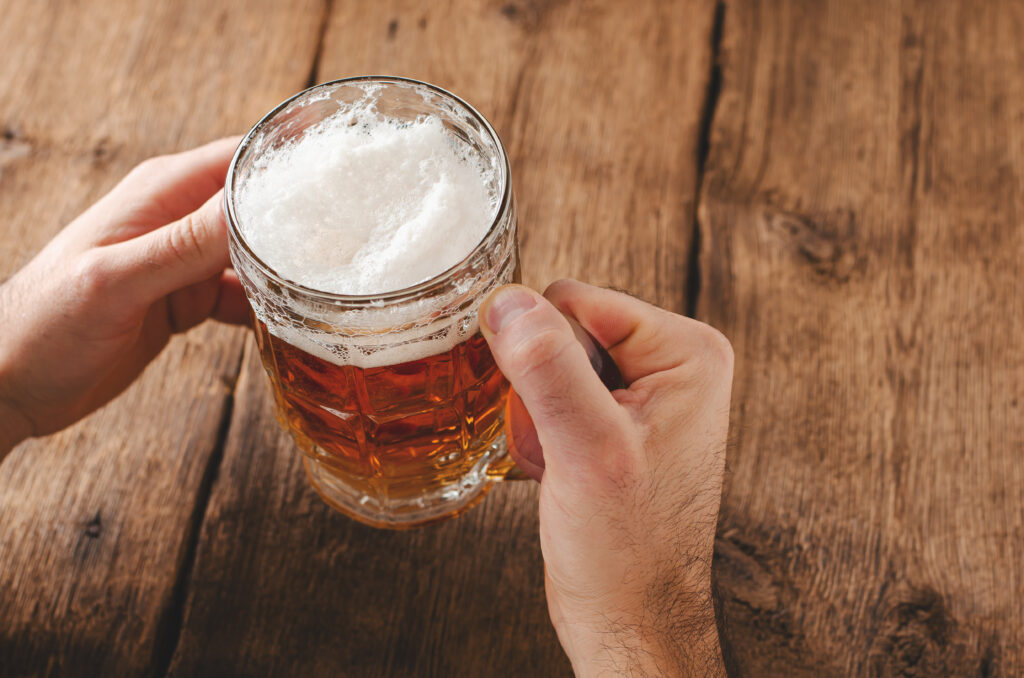 hands holding glass of blonde beer 